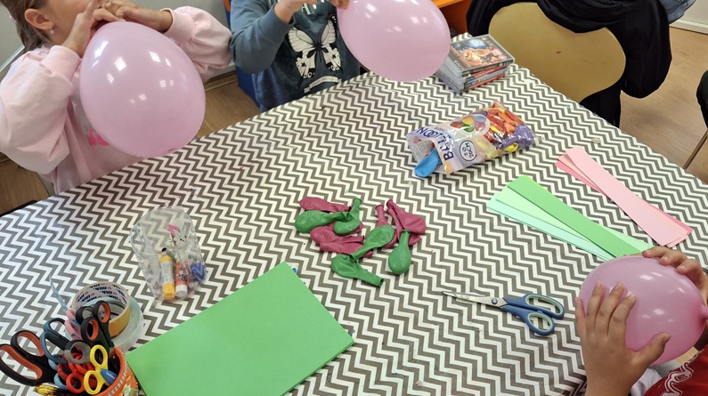 dzieci pompujące różowe i zielone balony