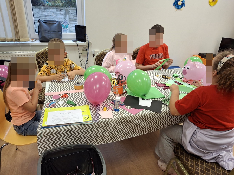 dzieci przy stole sklejające skoczki z balonów i papieru