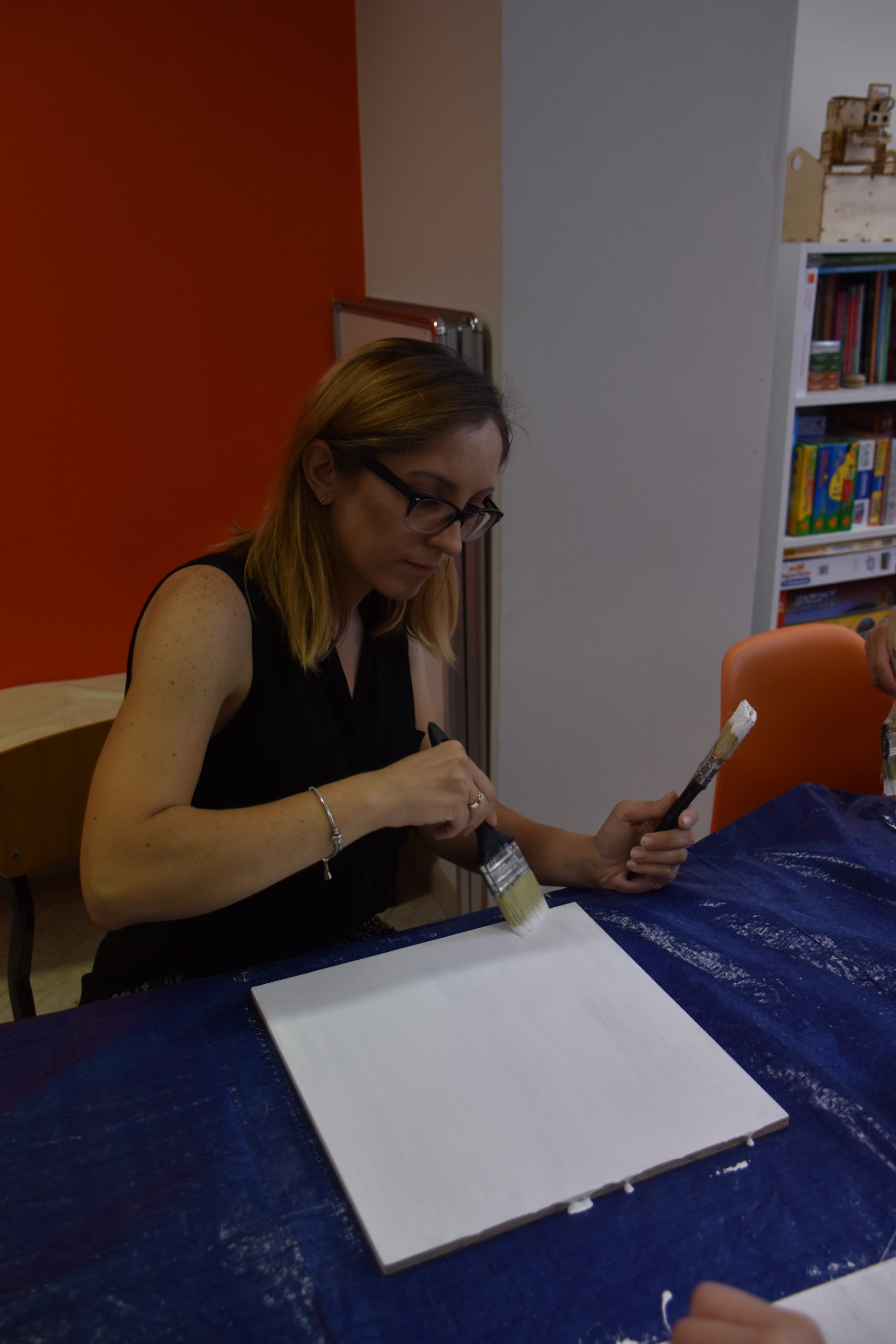 Animatorka Pracowni Orange, malująca kwadratową deskę na biały kolor.