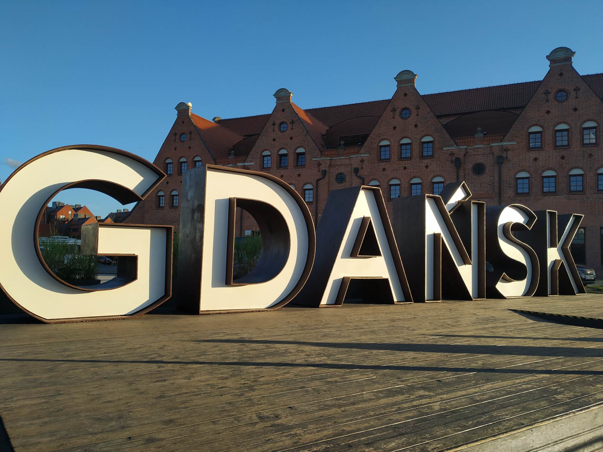 Zdjęcie napisu GDAŃSK na tle budynku z czerwonej cegły.