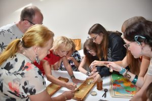Zdjęcie grupy warsztatowej wyjmująca łyżkami miód z plastrów