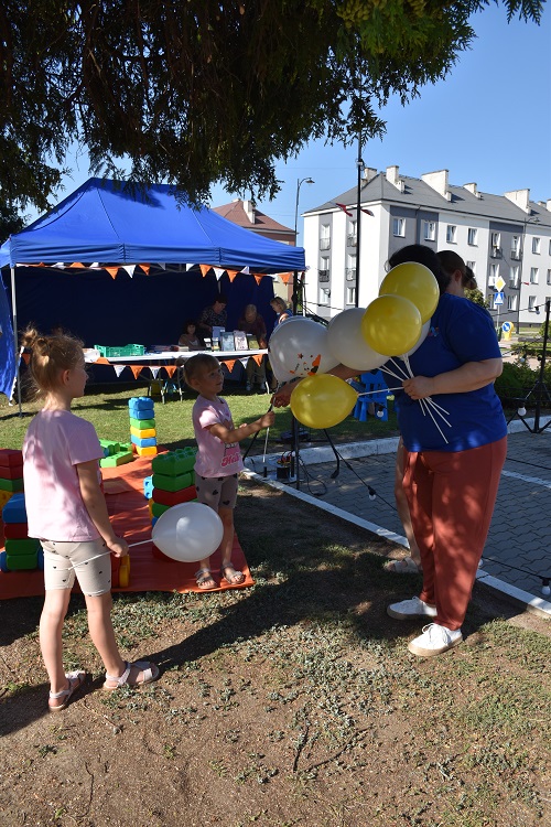 Pan rozdający balony dzieciom przy stoisku