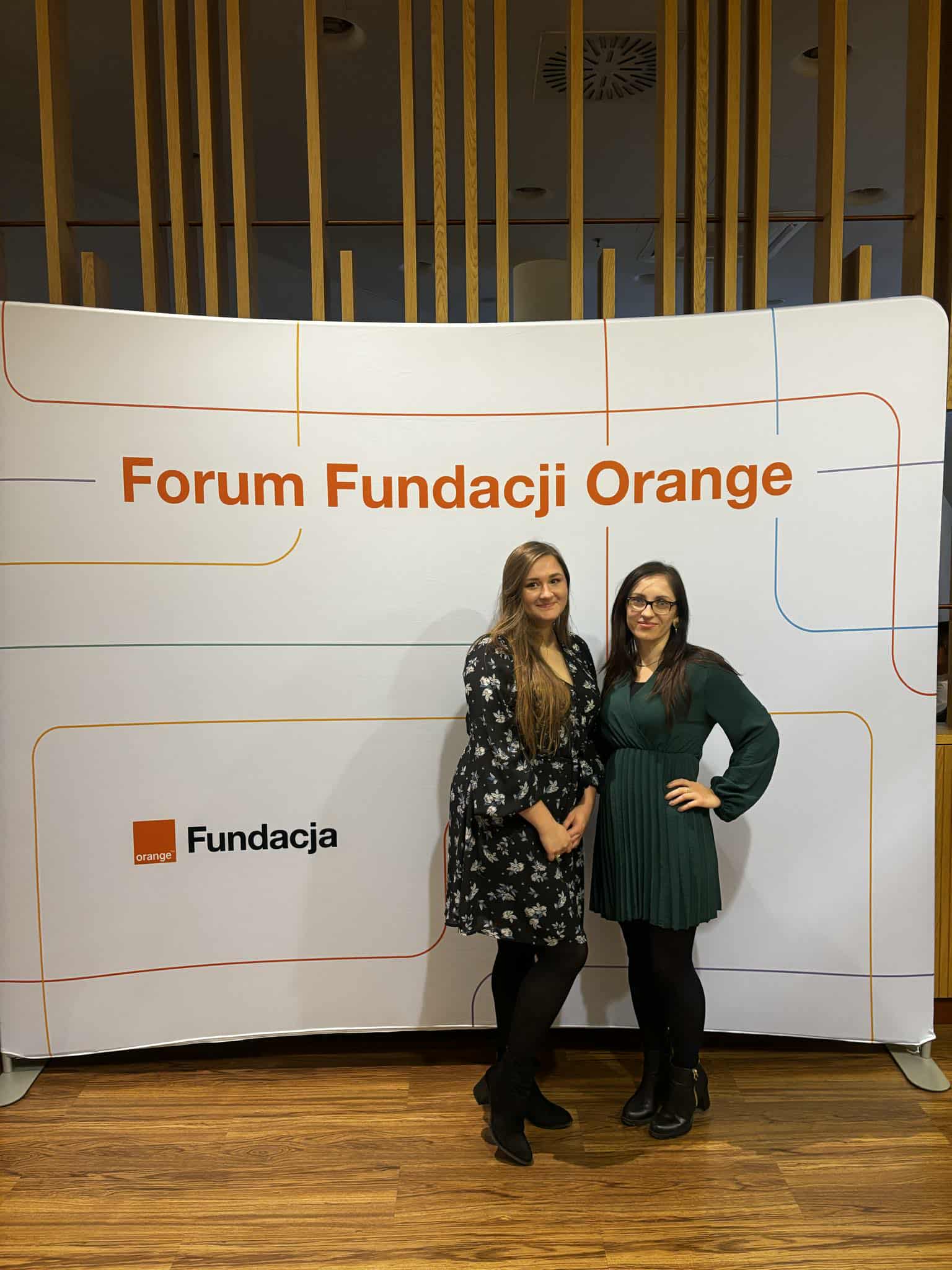 Dwie kobiety pozujące na ściance Fundacji Orange