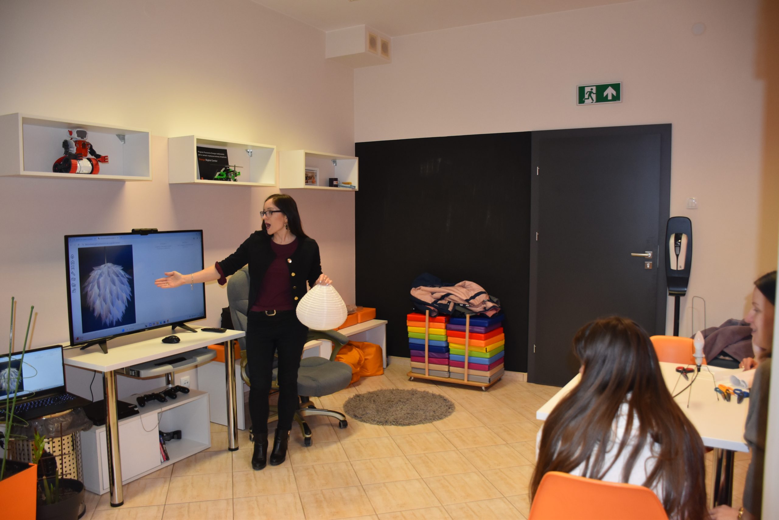 Prowadząca tłumaczy jak wykonać lampkę