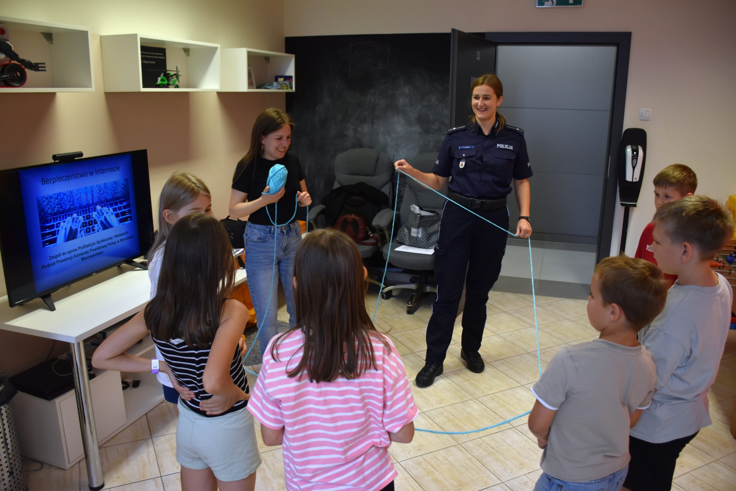 policjantka trzyma sznurek, przed nią stoją dzieci