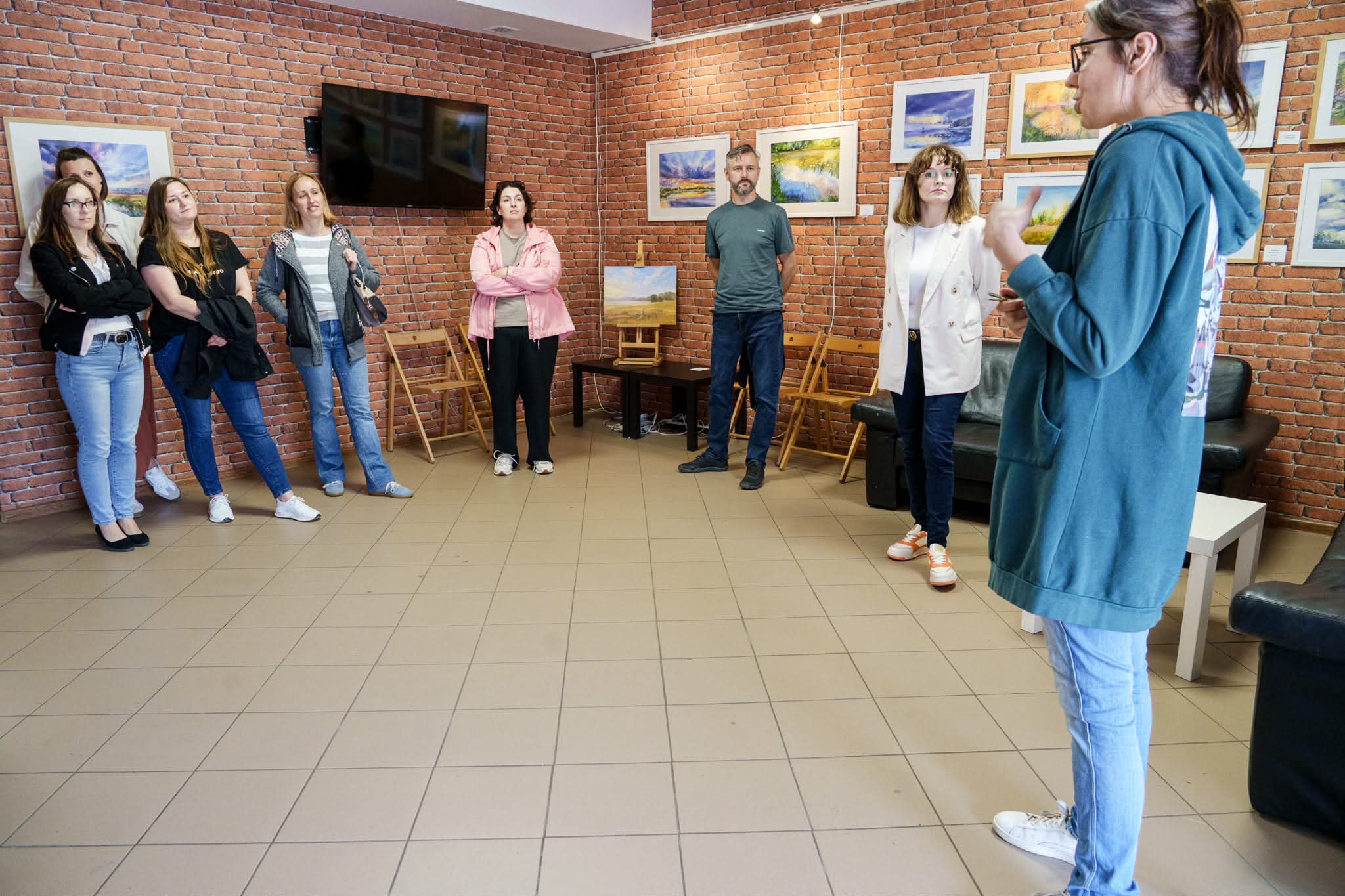 Grupa ludzi stojąca i słuchająca prowadzącej