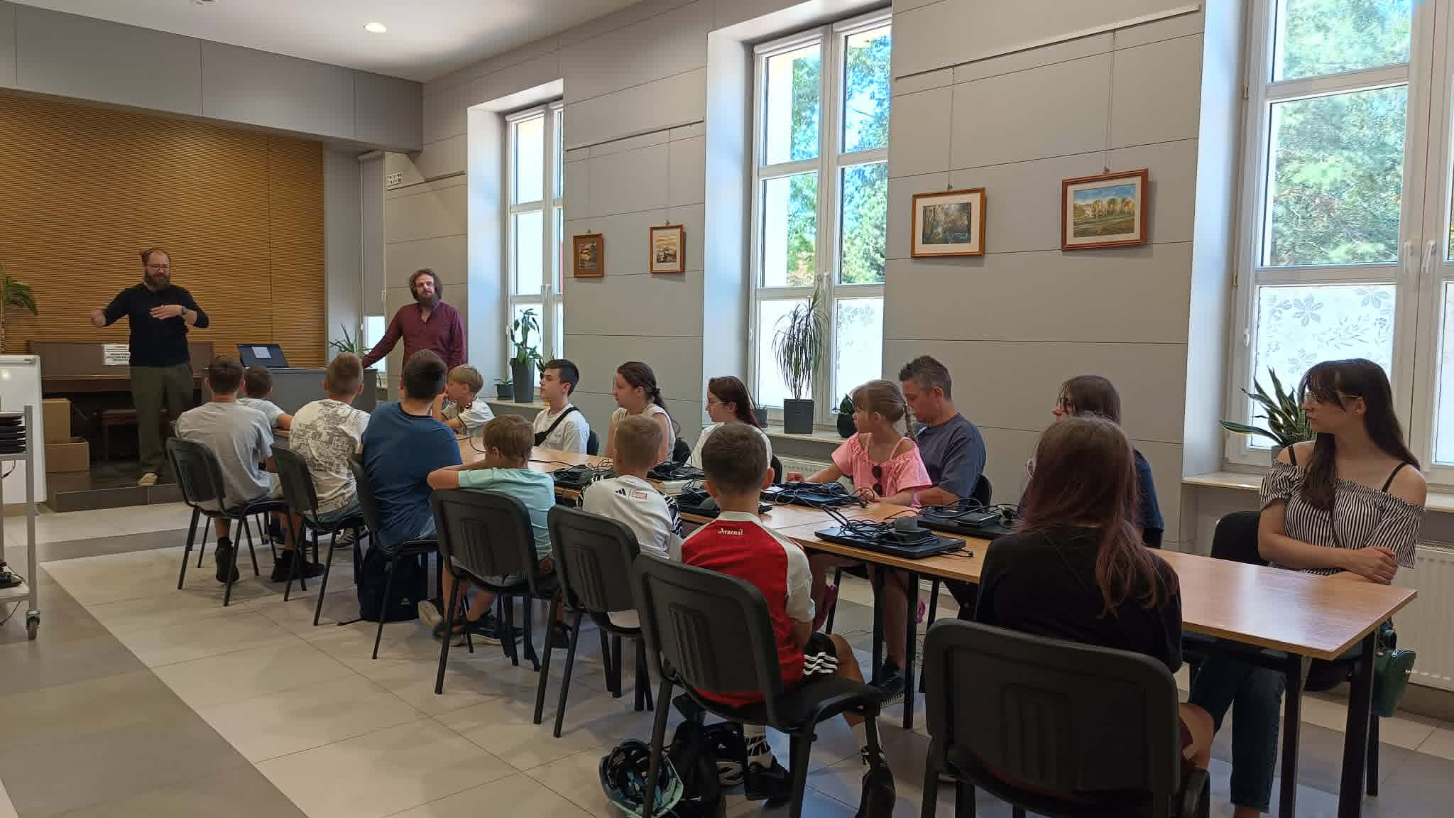przy długim stole siedzą uczestnicy zajęć