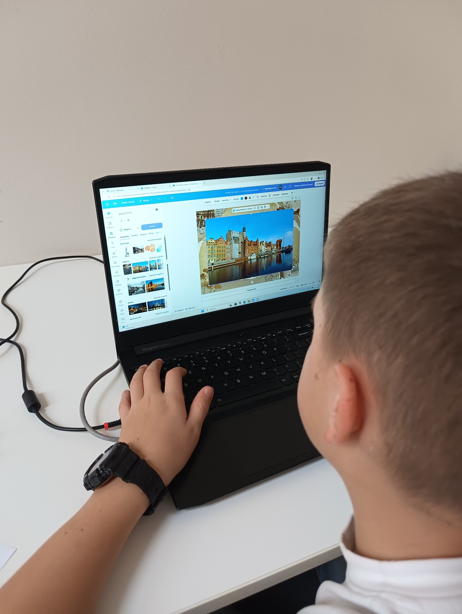 Chłopiec tworzy pocztówkę na laptopie