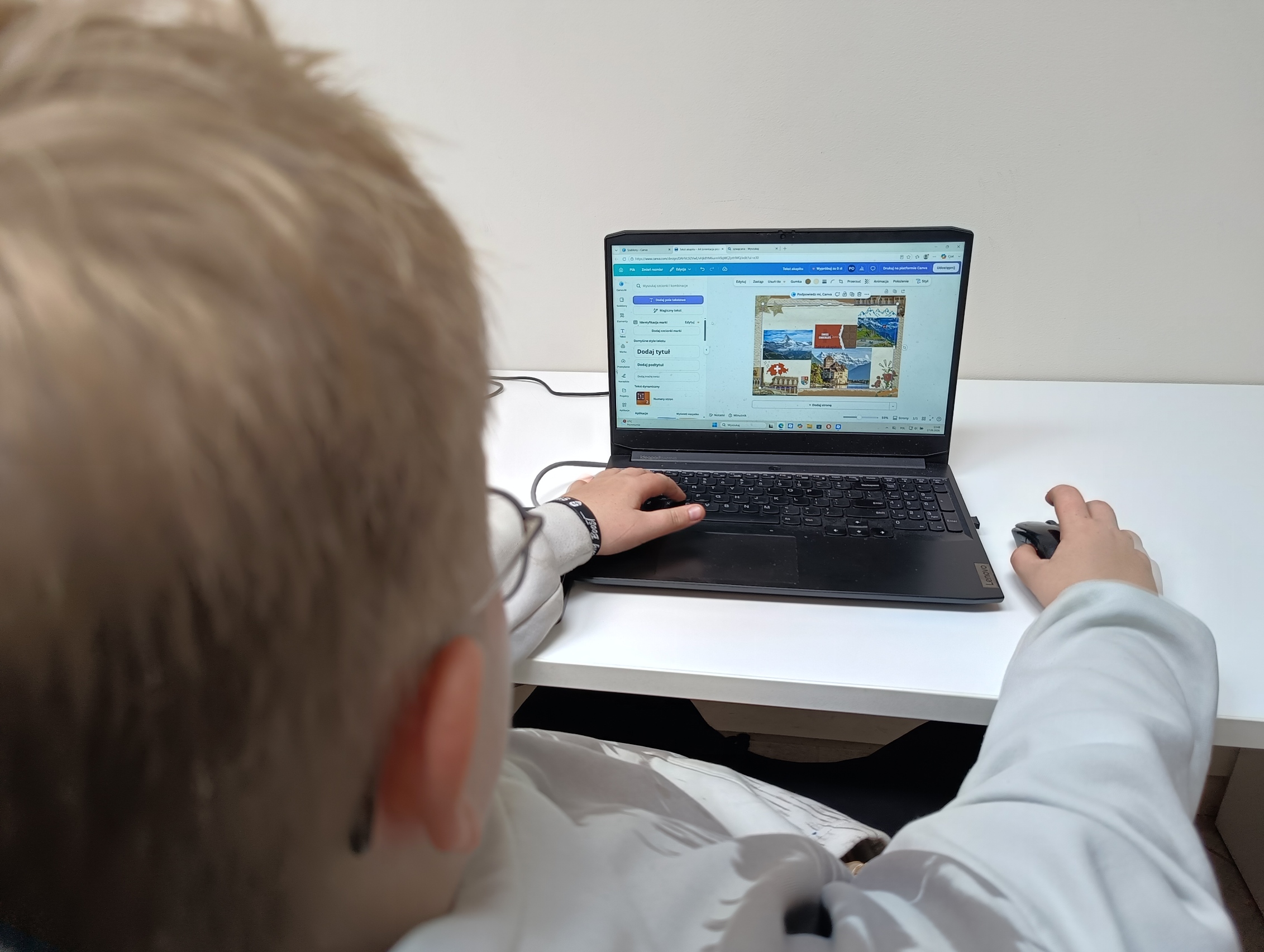 Chłopiec tworzy pocztówkę na laptopie