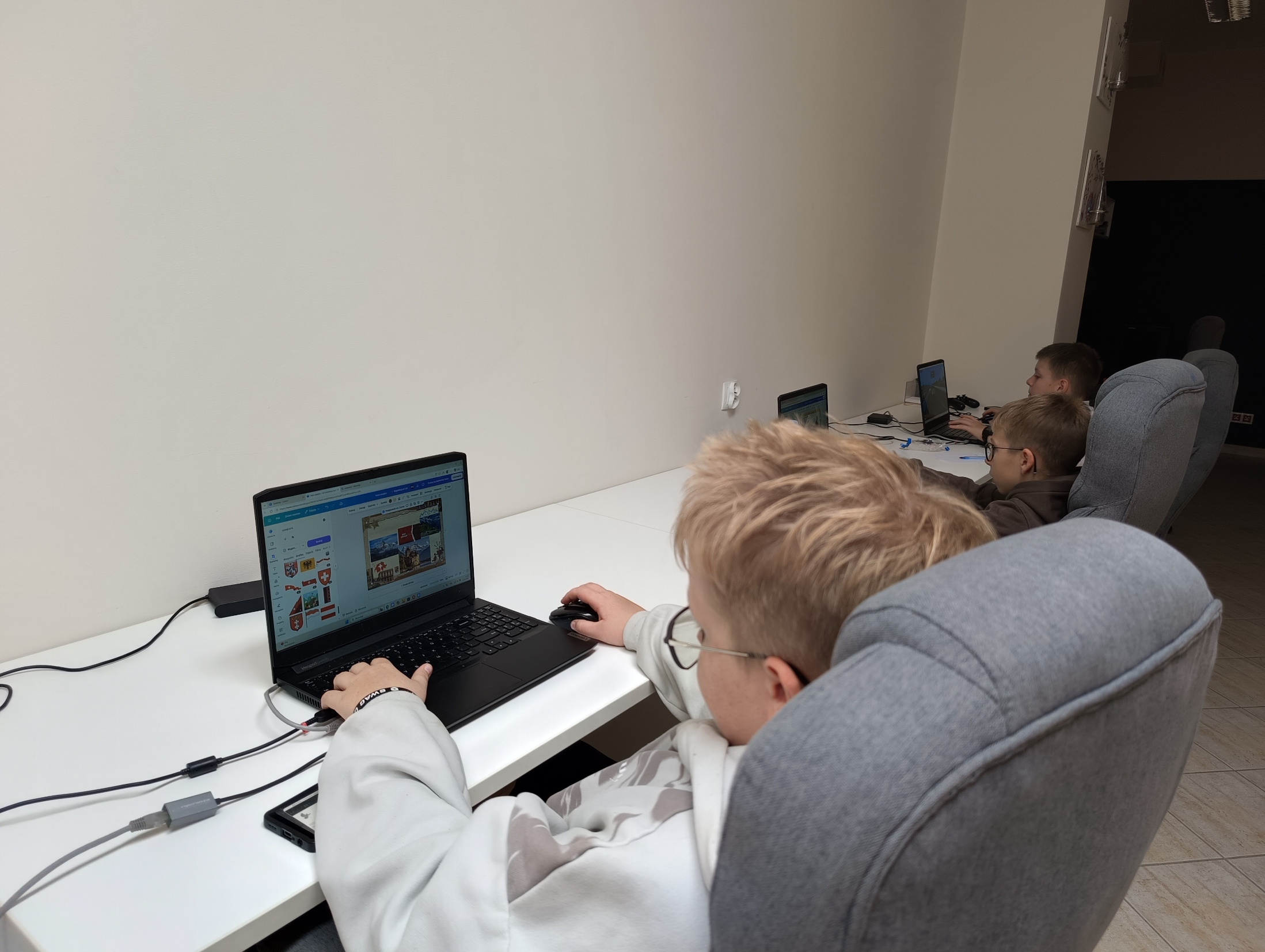 Trzej chłopcy pracujący przy laptopach