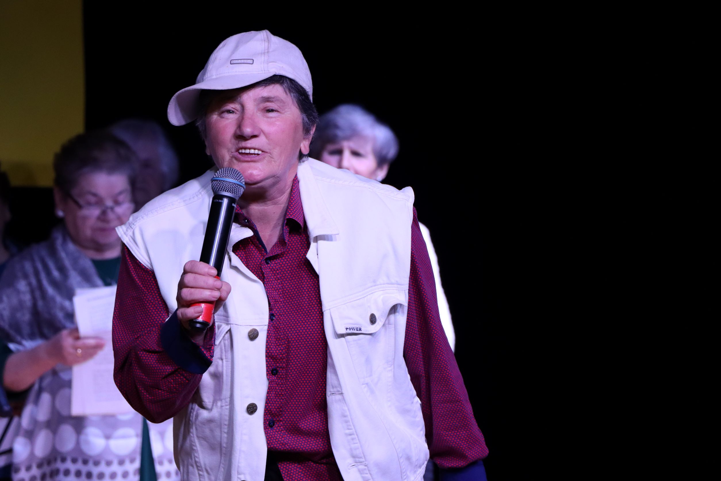 Kobieta stojąca z mikrofonem na scenie