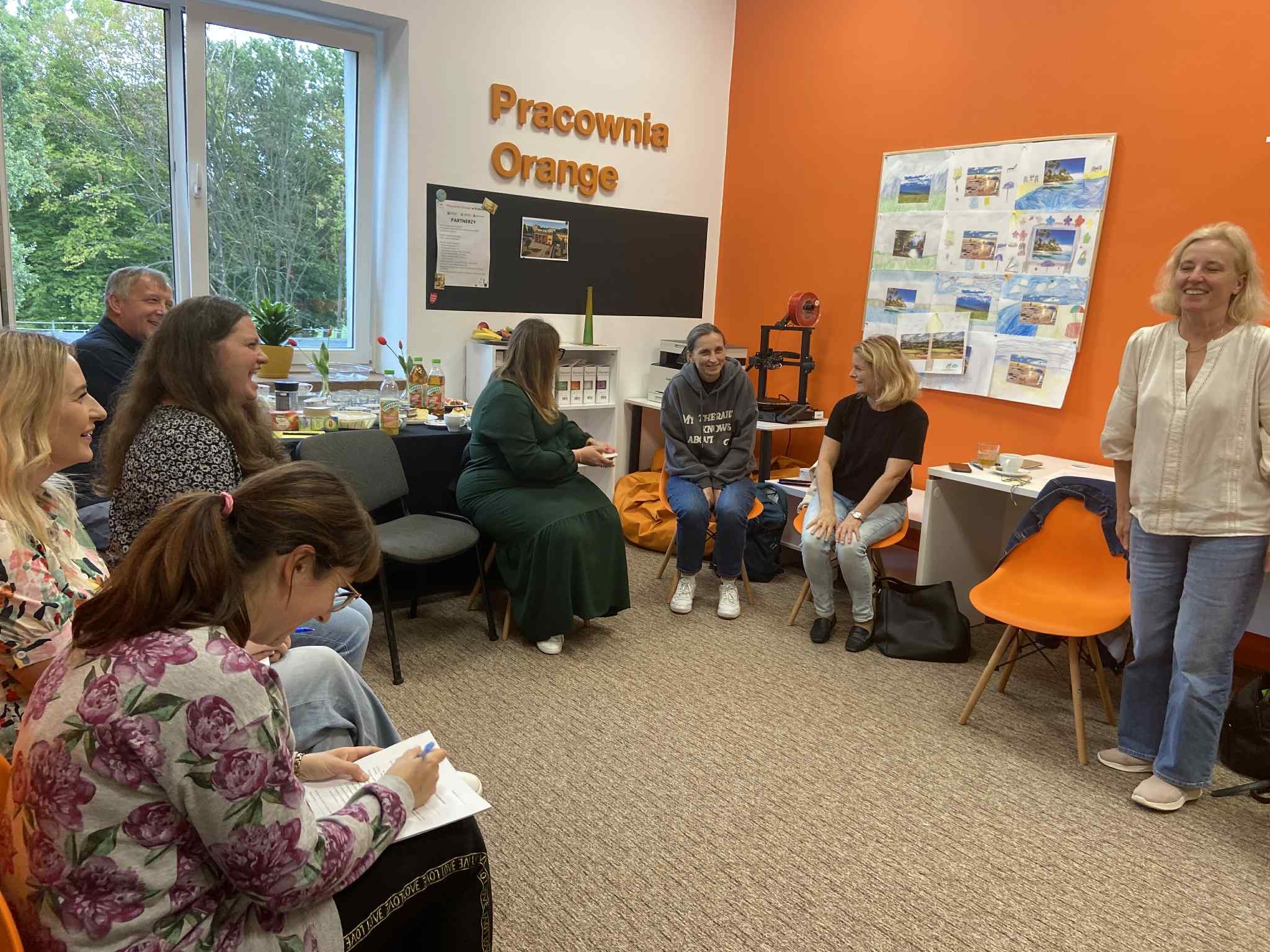 Grupa osób w Pracowni Orange, rozmawiających ze sobą