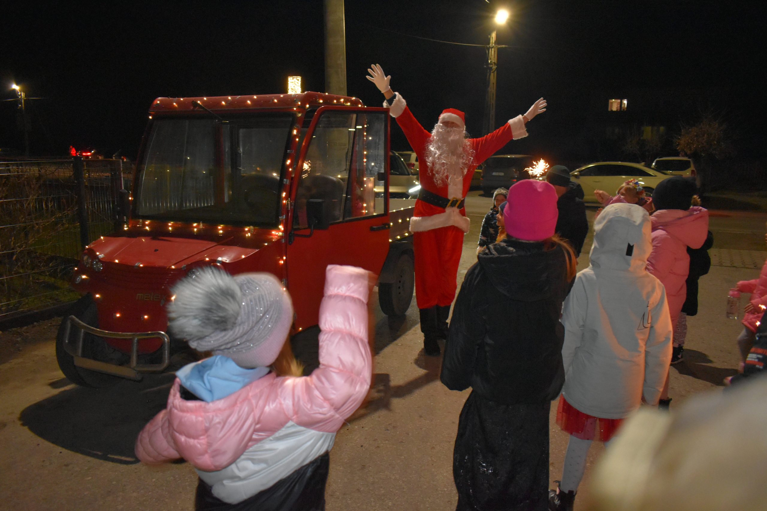 Zdjęcie przedstawiające osobę w stroju św. Mikołaja i machające mu dzieci.