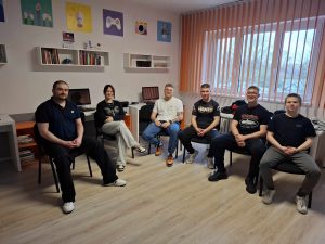 Grupa mężczyzn siedzi w kręgu na krzesłach.