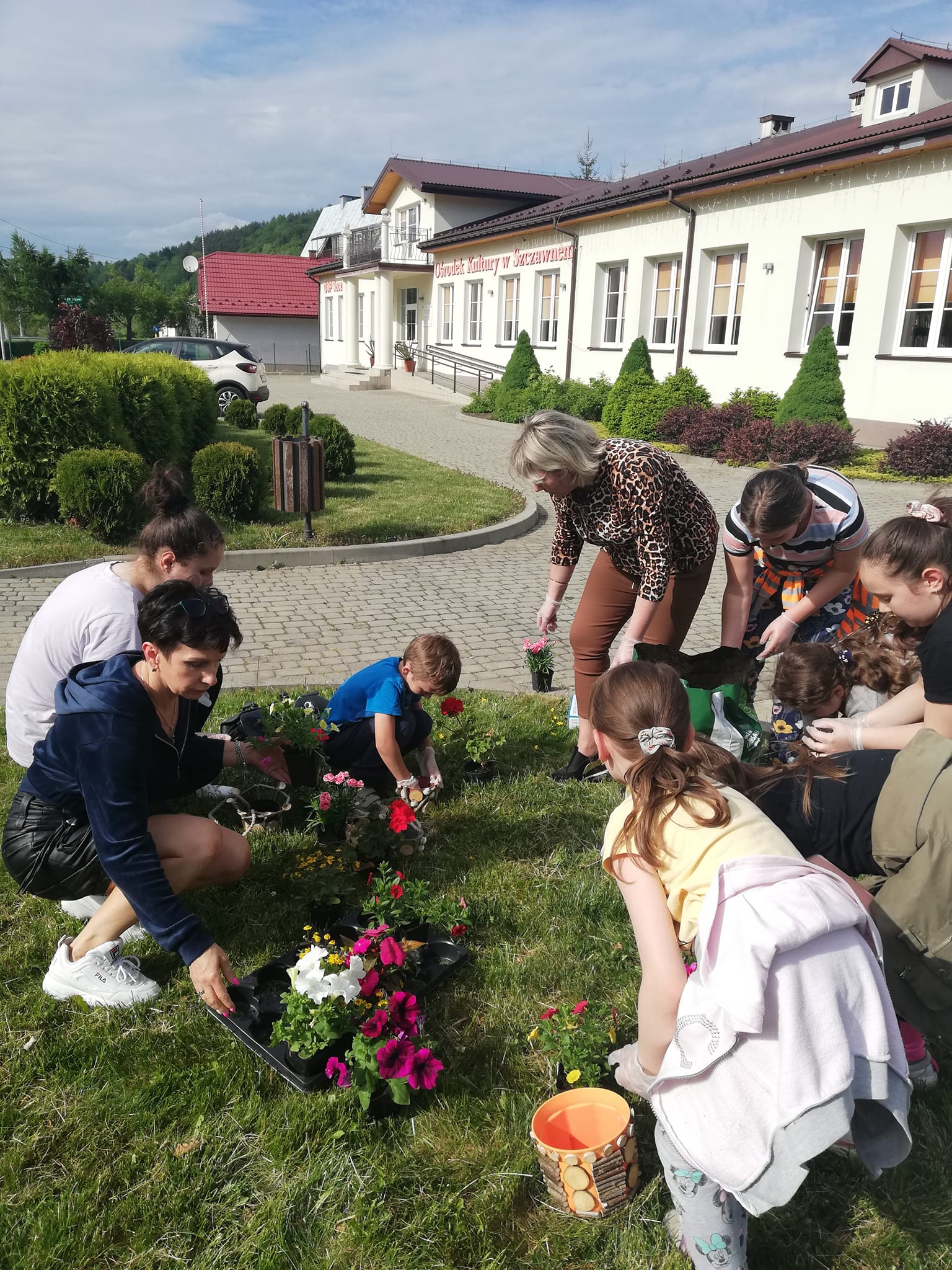 grupa dzieci i młodzieży sadzi kwiatki dla seniorów
