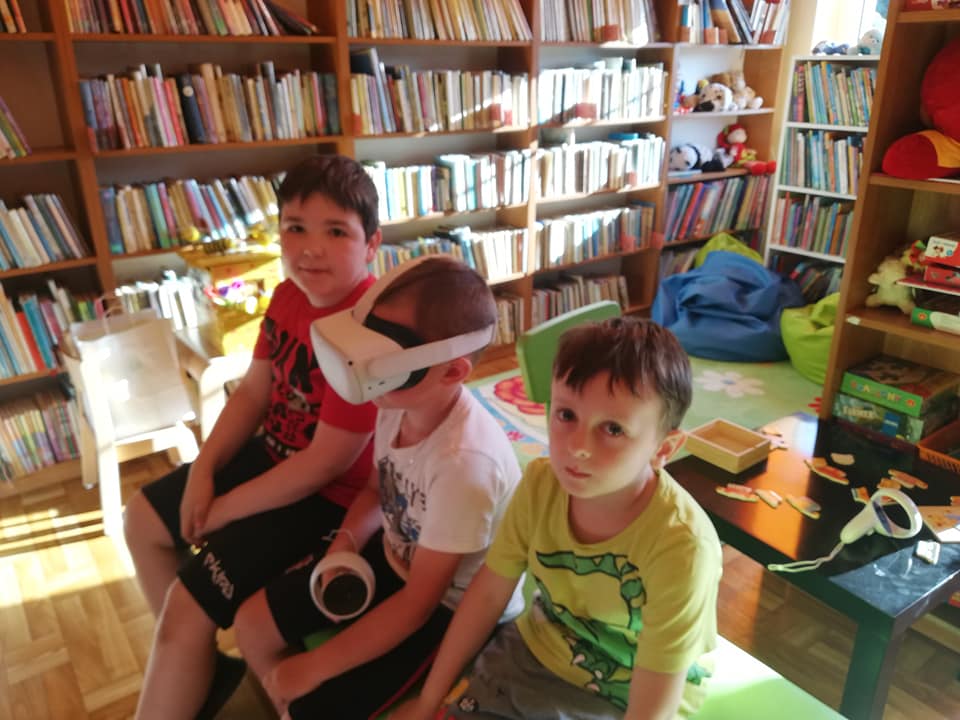 trzej chłopcy w bibliotece z goglami VR