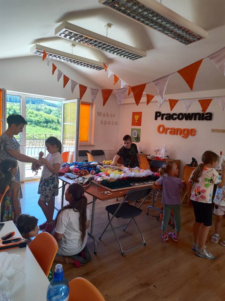 zdjęcie pomieszczenia Pracowni Orange wypełnionego uczestnikami tworzącymi upcyklingową ścianę sensoryczną