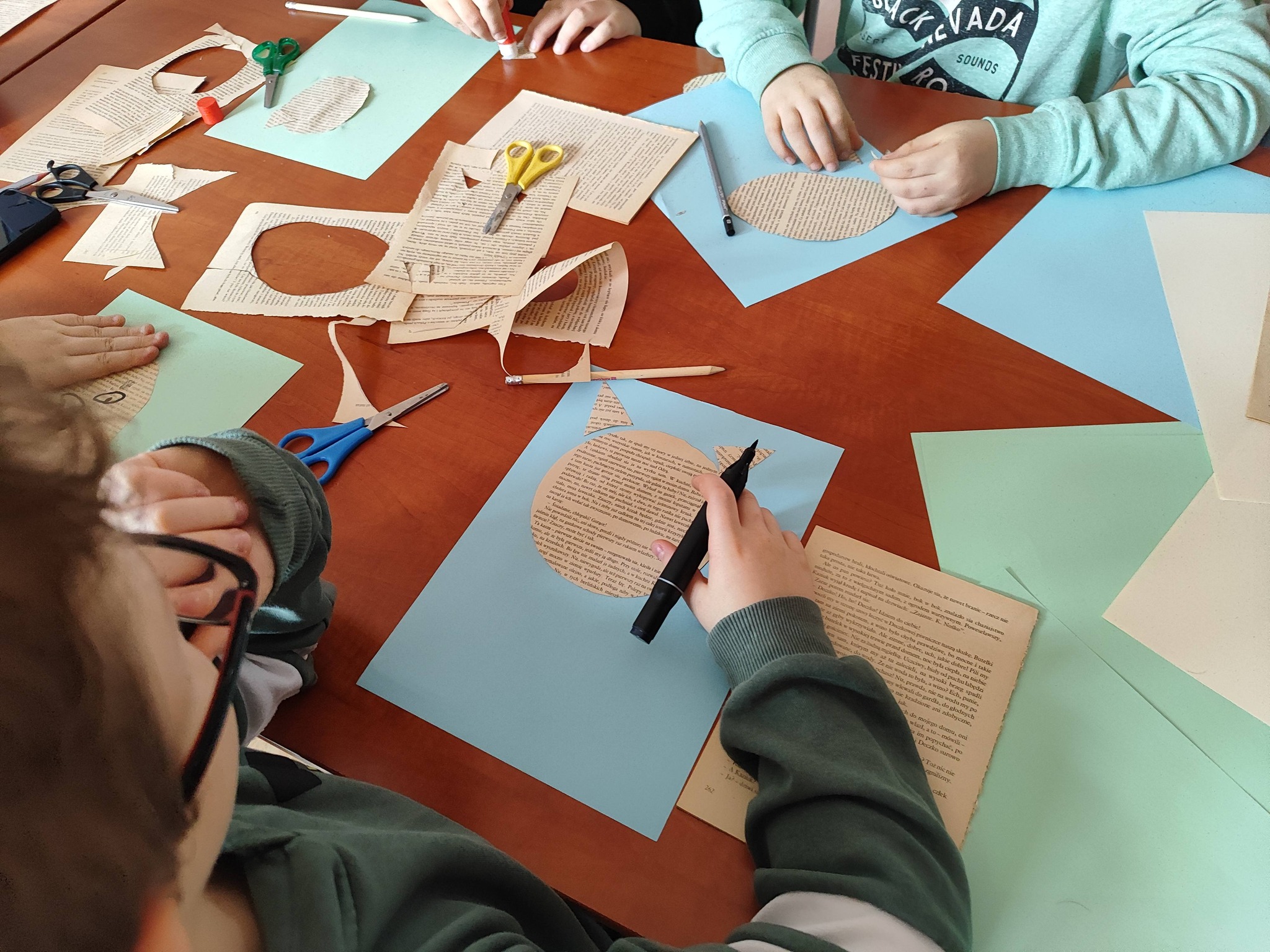 Dzieci siedzą przy stole i tworzą kocie portrety