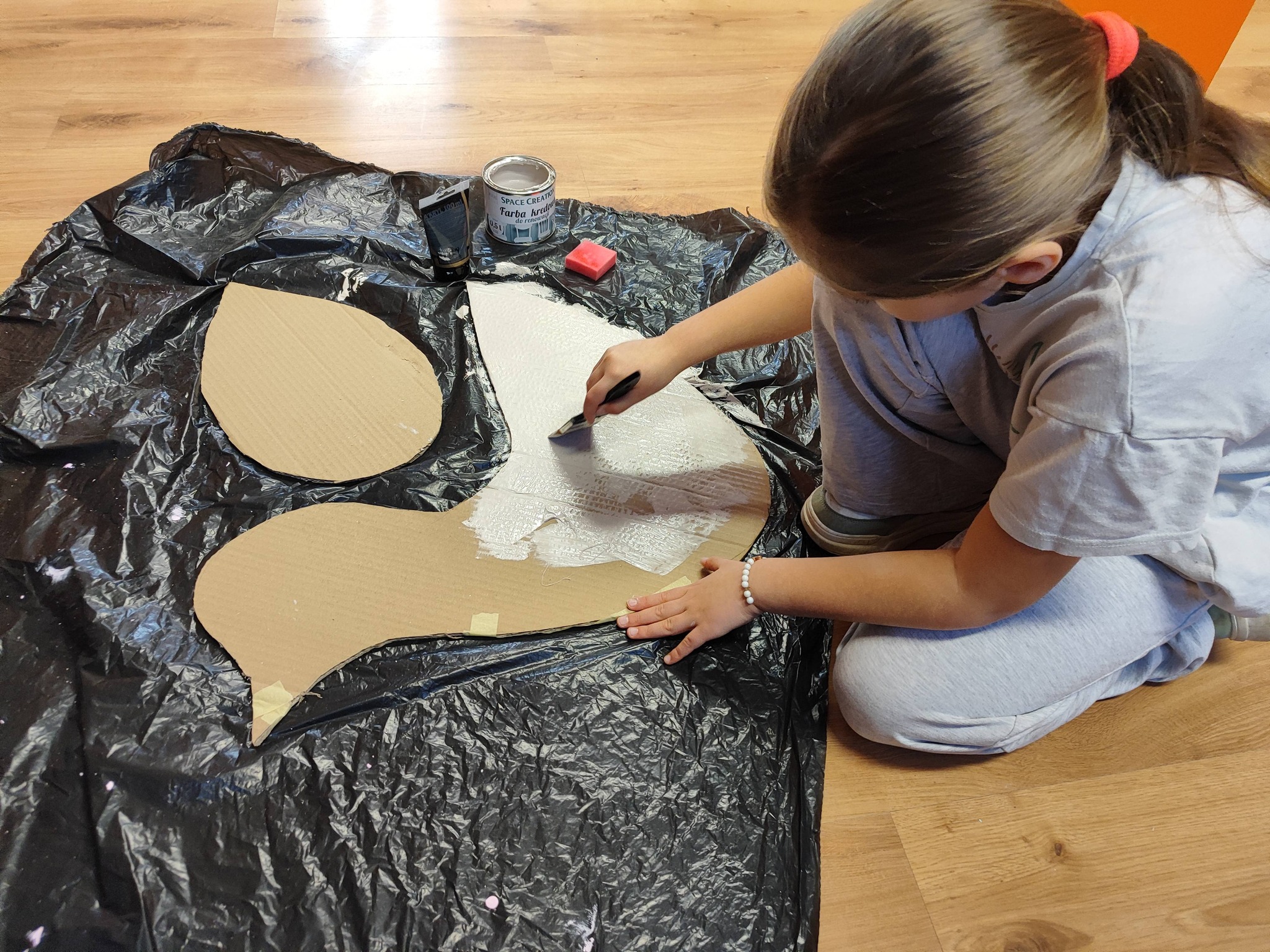 dziewczynka maluje ptaka z tektury