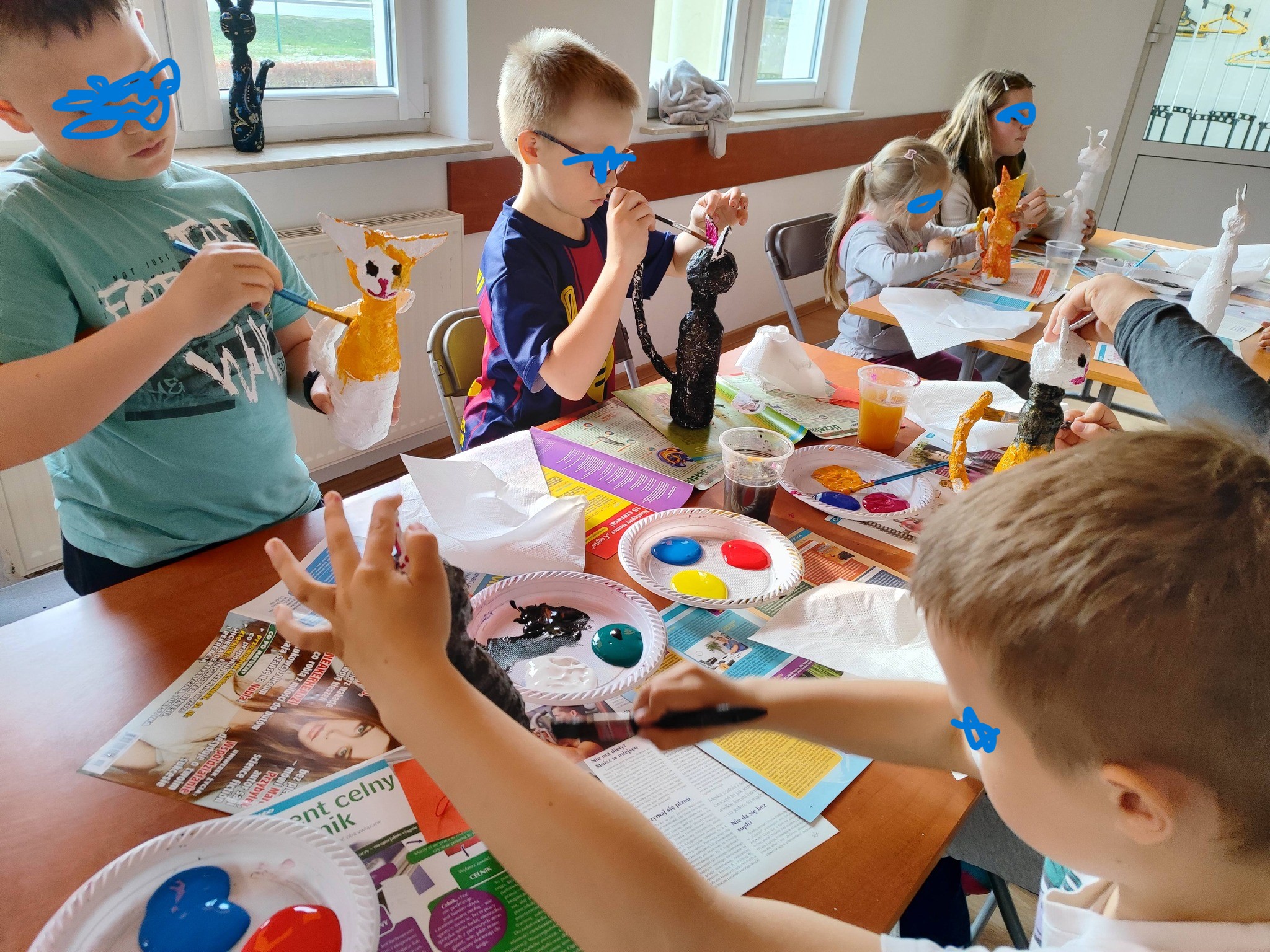 dzieci i młodzież malują figurki kotów