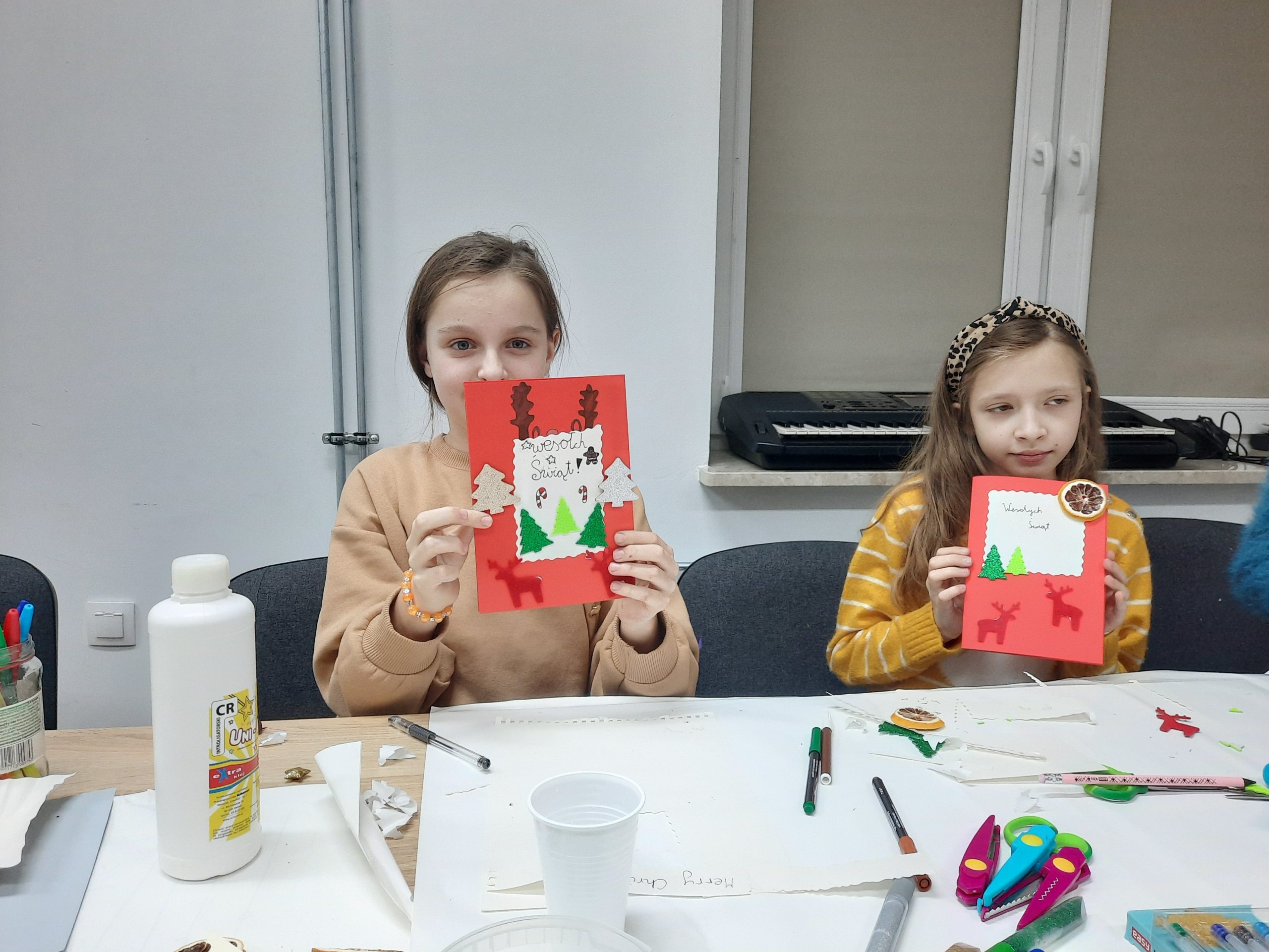 dwie dziewczynki pozują do zdjęcia ze swoimi kartkami świątecznymi