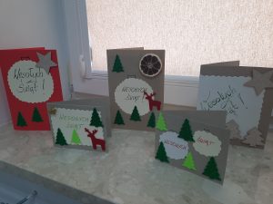 Na zdjęciu widoczne są kolorowe kartki świąteczne stojące na parapecie w oknie.