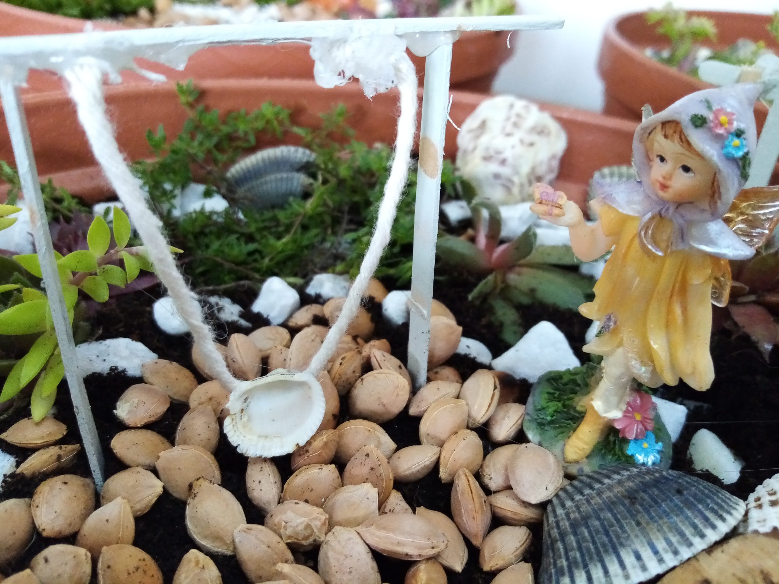 Zdjęcie, fragment ogrodu wróżek - zabawka wróżka, rośliny.