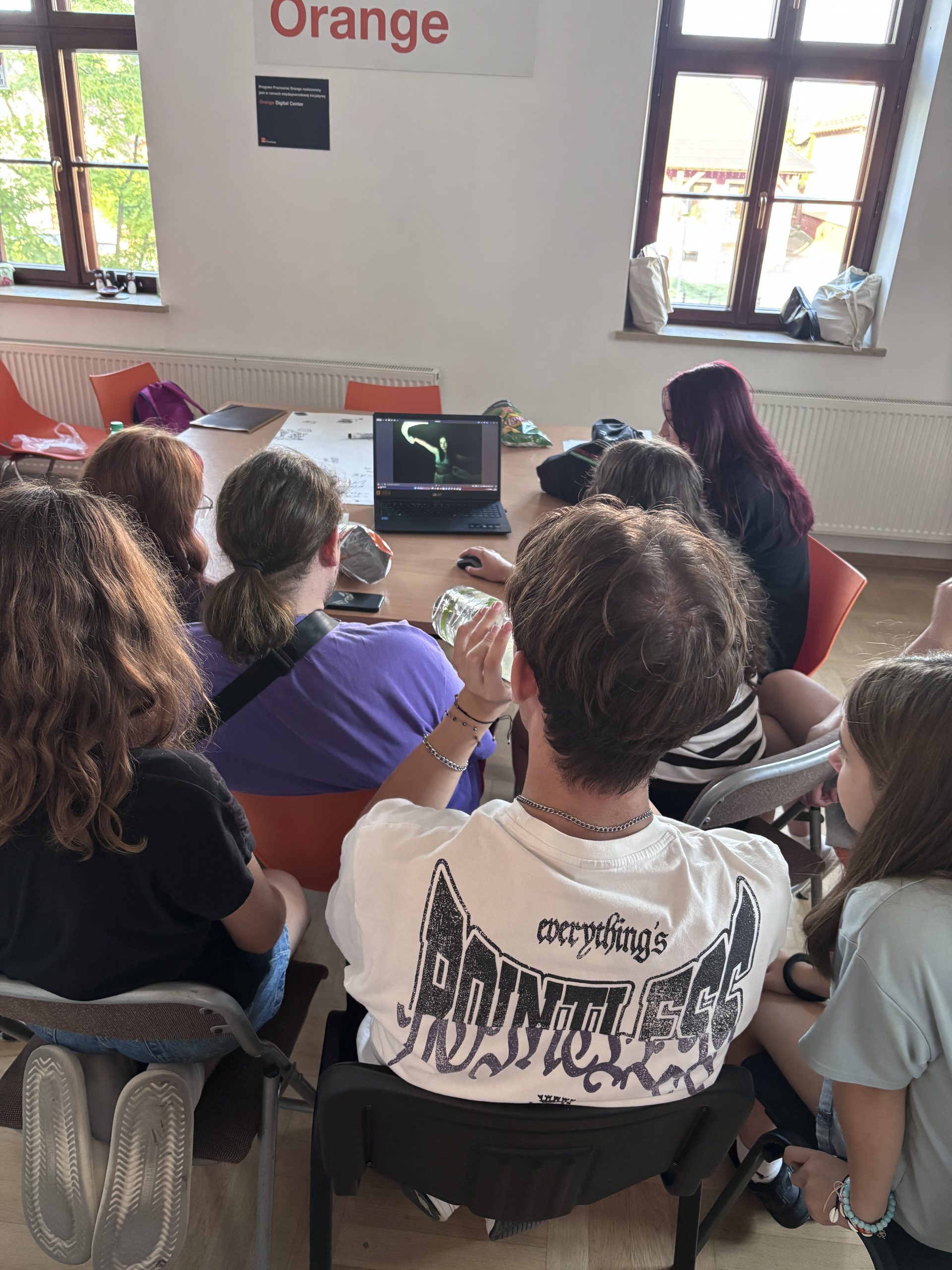 Grupa dzieci oglądająca film na laptopie.