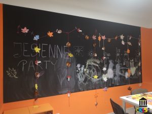 Na zdjęciu widać jesienną girlande, wykonana z kolorowych liści , zawieszoną na ścianie