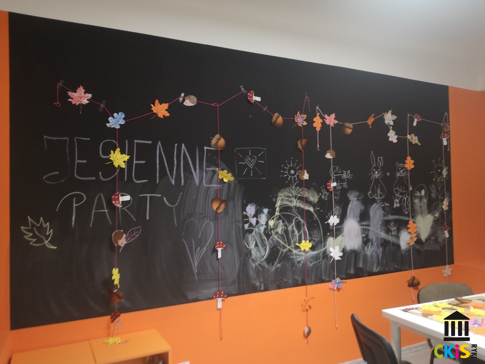 Na zdjęciu widać jesienną girlande, wykonana z kolorowych liści , zawieszoną na ścianie