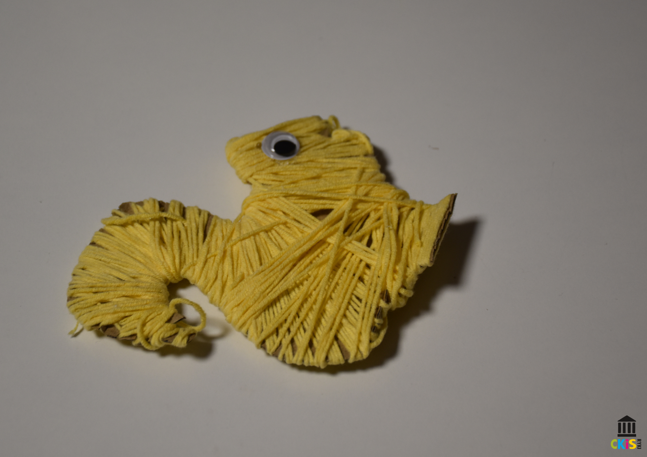 Na obrazku widać wiewiórkę wykonaną z żółtej wełny.