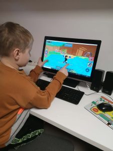 na zdjęciu widać chłopca, który gra na komputerze