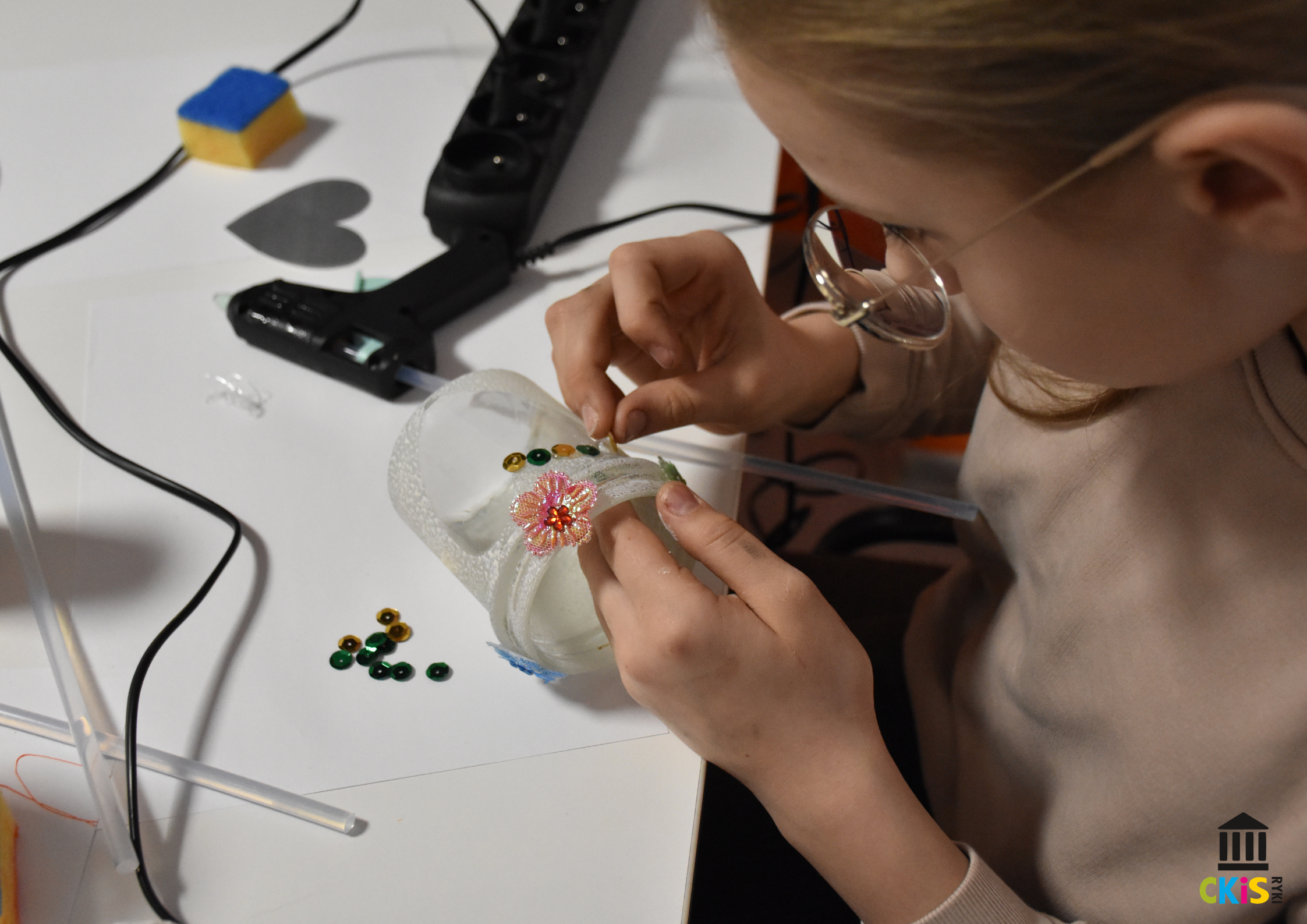 na zdjęciu widać dziewczynkę, która ozdabia słoik cekinami