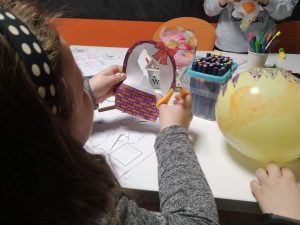 na zdjęciu widać dziewczynkę trzymającą koszyczek wycięty z papieru