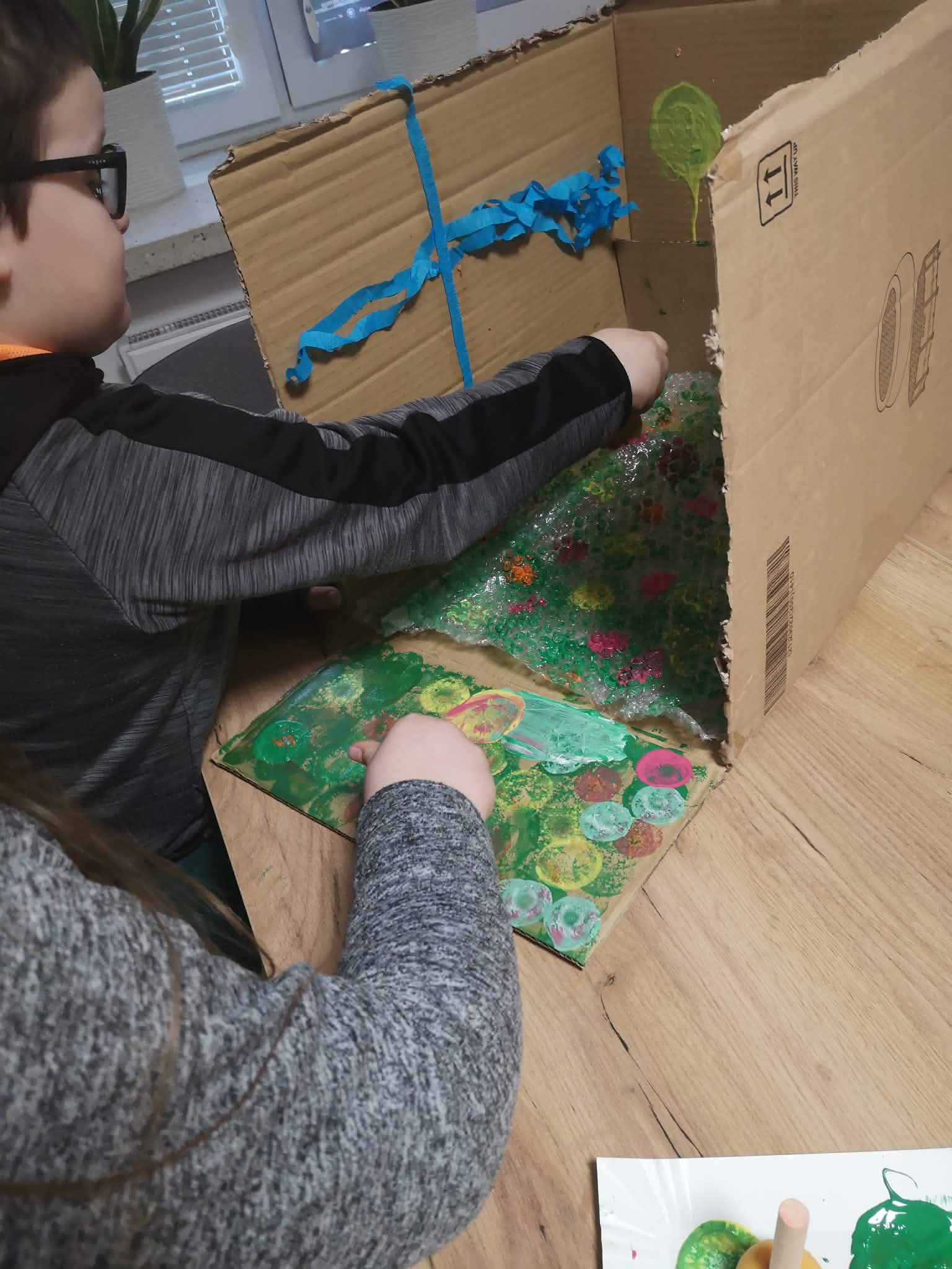 na zdjęciu widać dzieci malujących karton