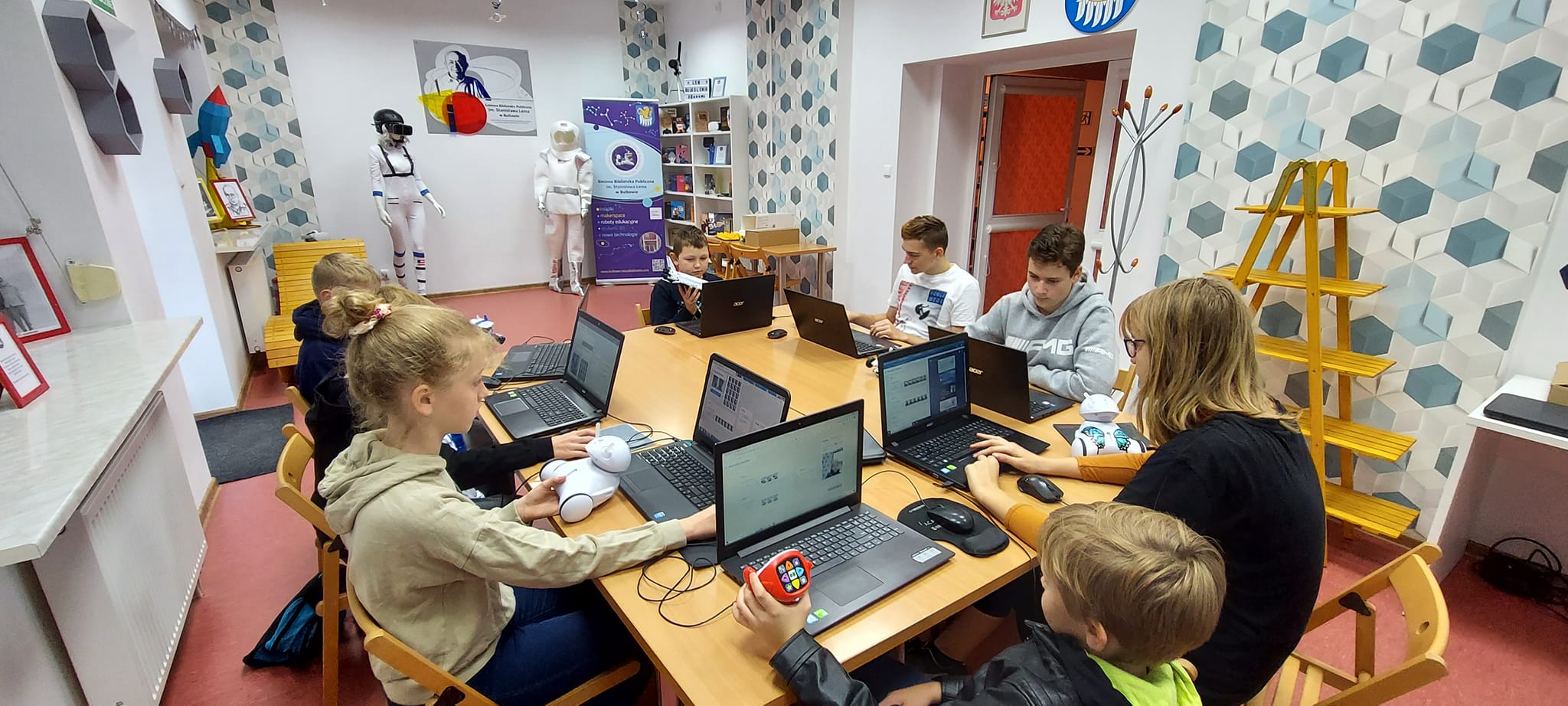 Grupa dzieci siedzących przy komputerach podczas projektowania własnych zabawek.