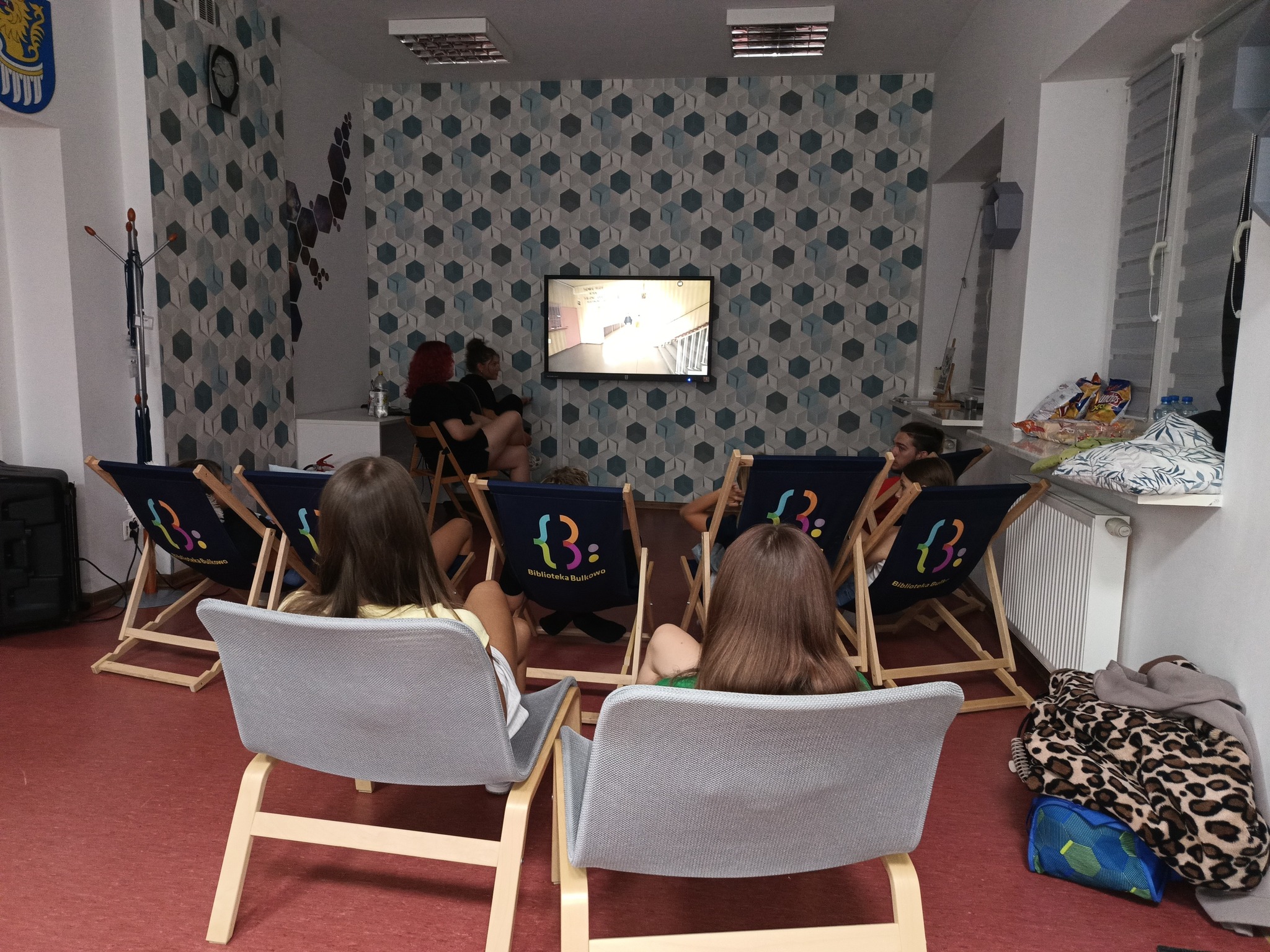 uczestnicy leżą na leżakach i fotelach, oglądają film edukacyjny