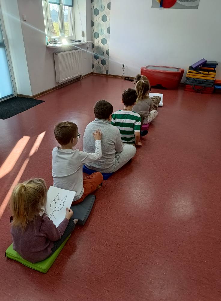 dzieci siedzą w rzędzie i rysują dotykiem