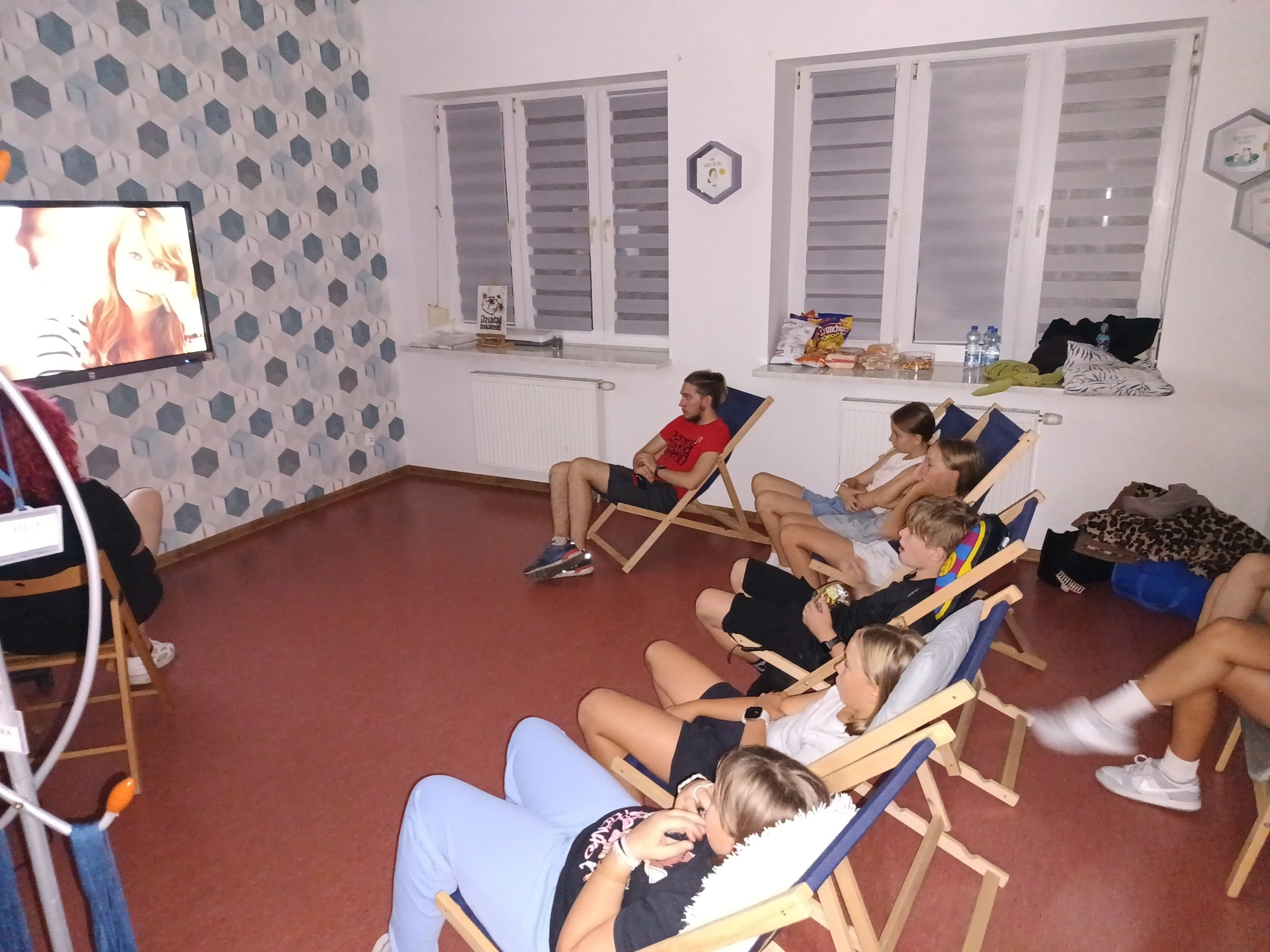 uczestnicy leżą na leżakach i oglądają film familijny