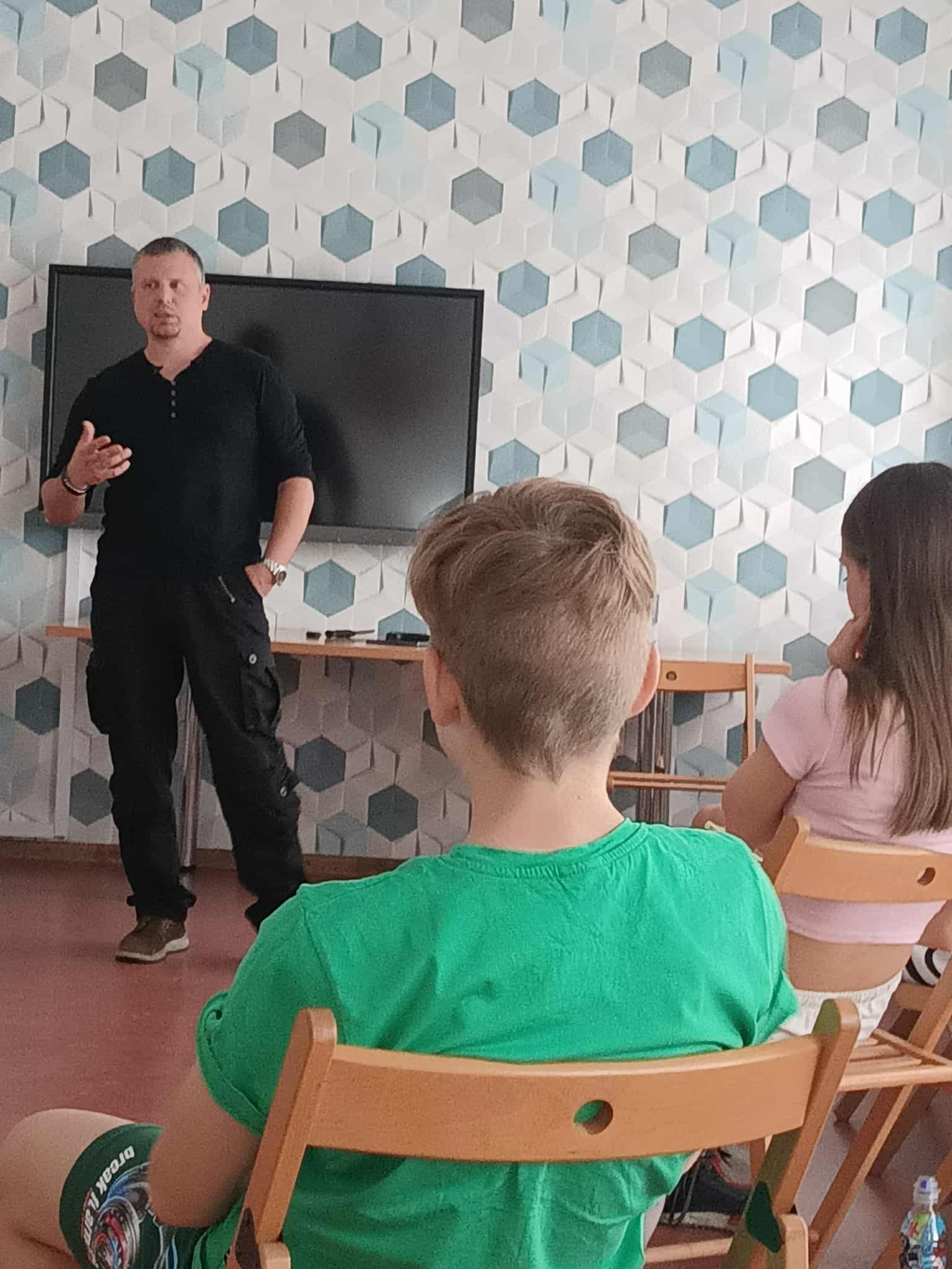 uczestnicy siedzą w kole na krzesełkach prowadzący prowadzi prelekcję