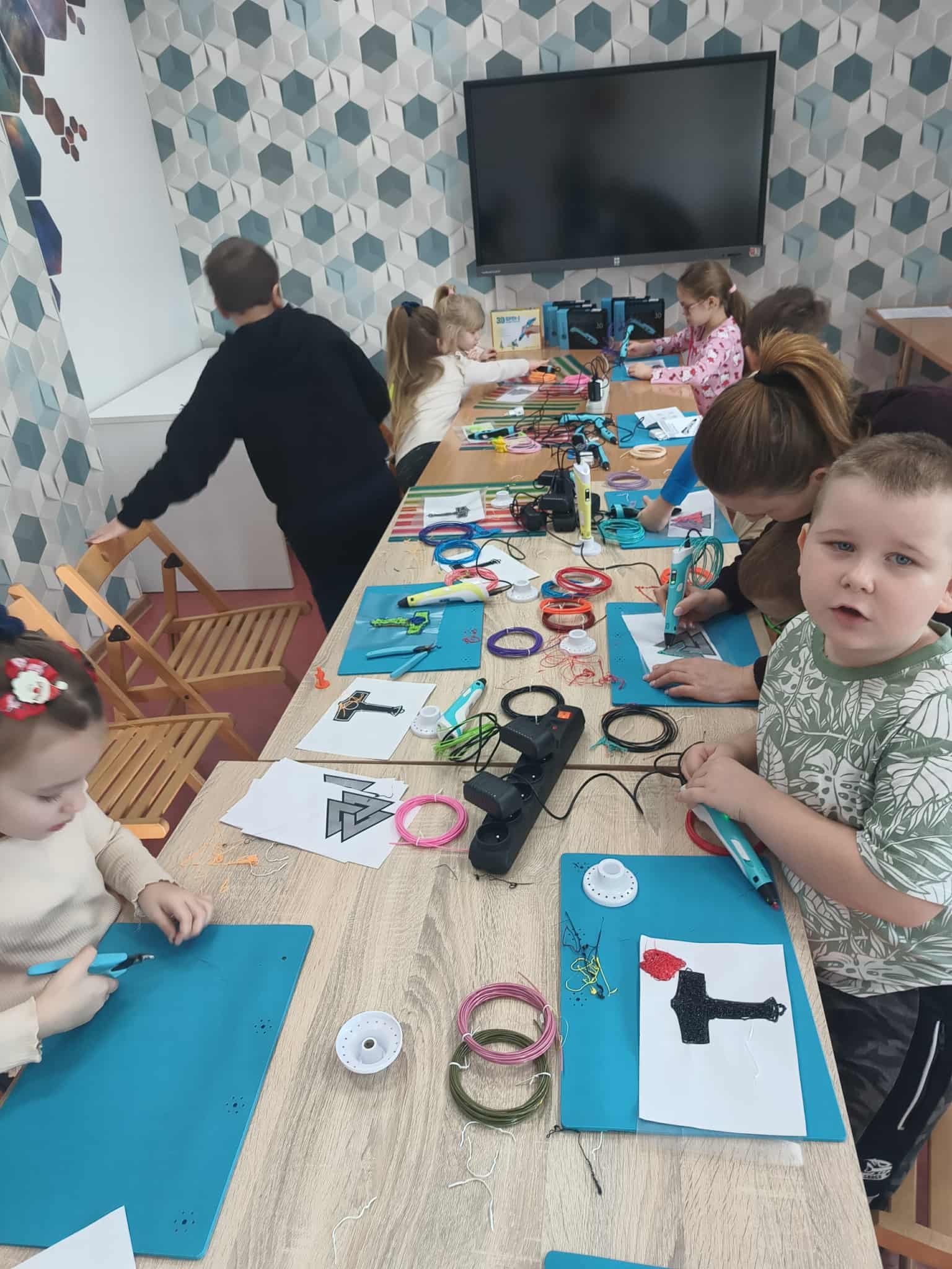 uczestnicy siedzą przy stoliku i wykonują symbole Wikingów długopisem 3d