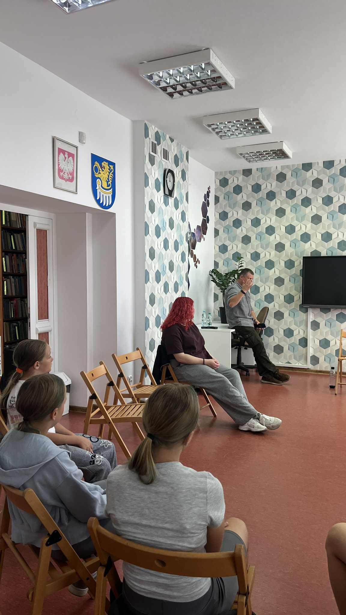 część uczestników siedzi na krzesełkach słuchając prowadzącego