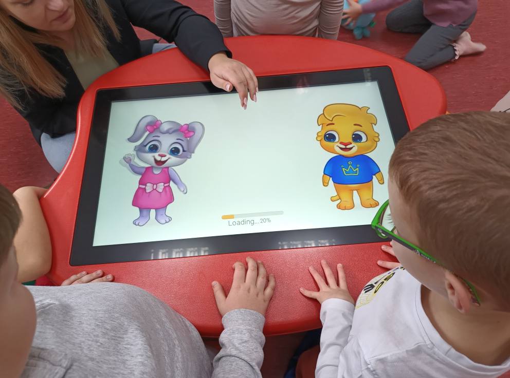 dzieci wspólnie grają na stoliku edukacyjnym