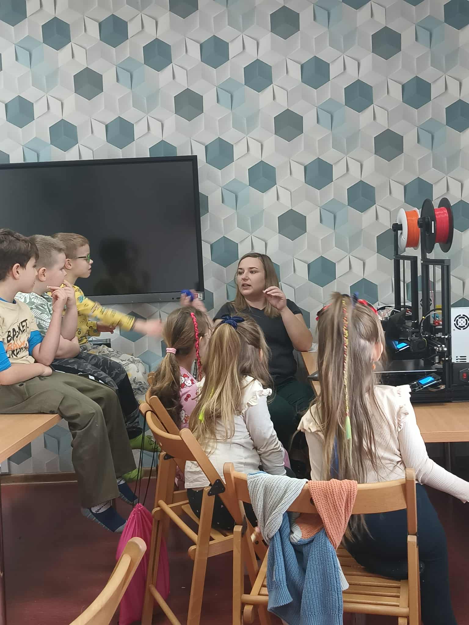 prowadząca opowiada dzieciom jak działa drukarka 3d