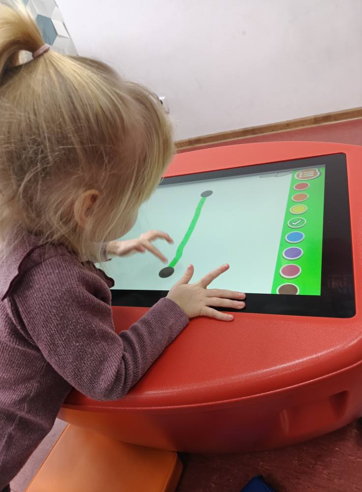 dziewczynka rysuje na stoliku edukacyjnym
