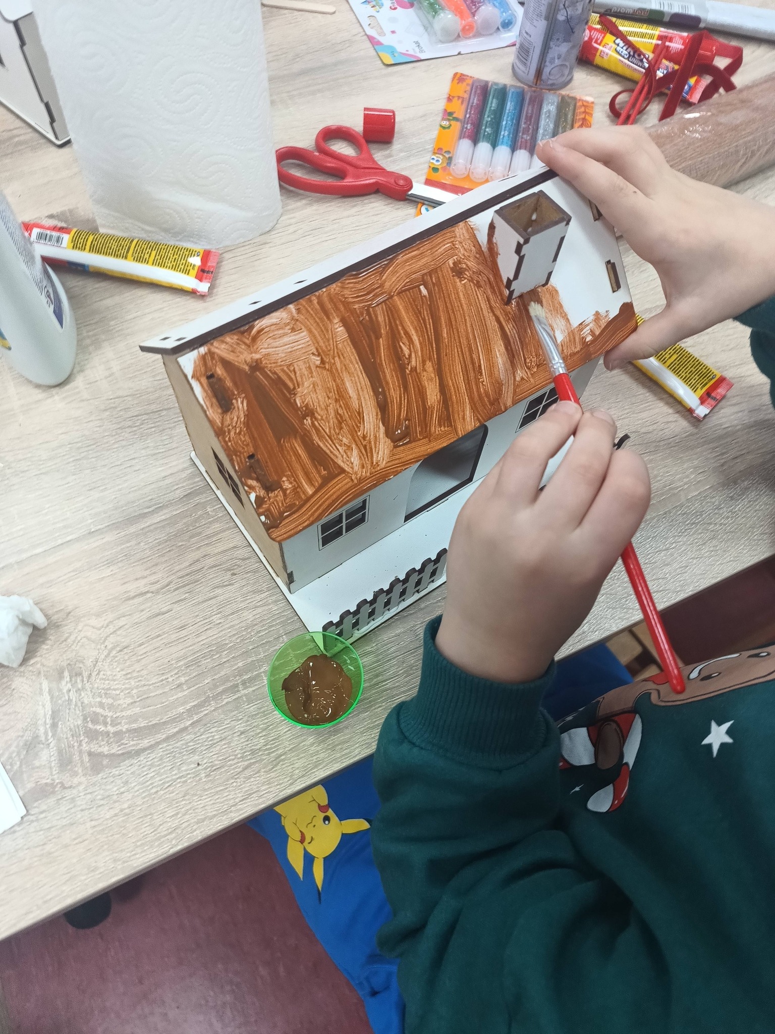 dziecko maluje domek na brązowo