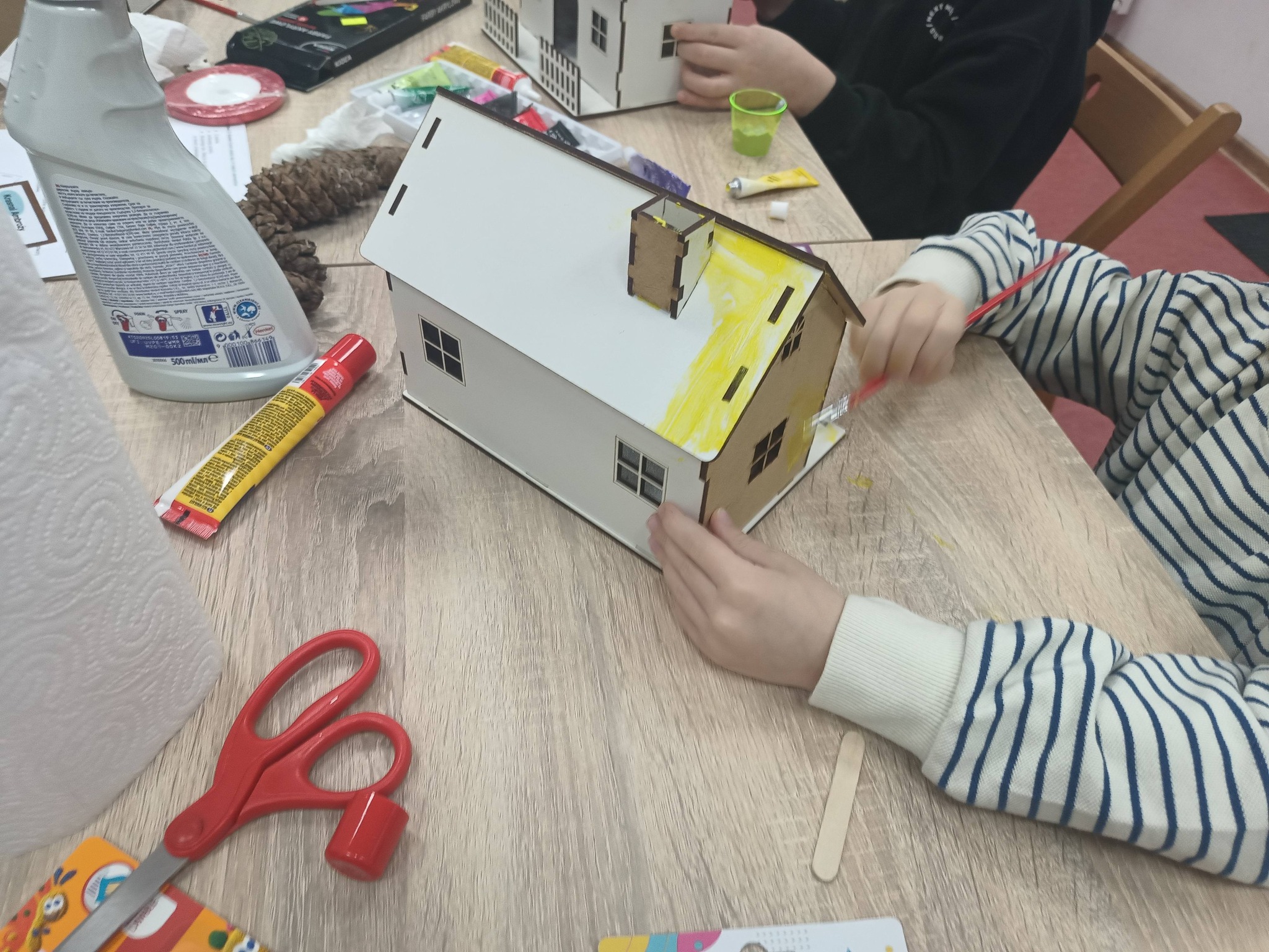 dziecko maluje domek na żółto