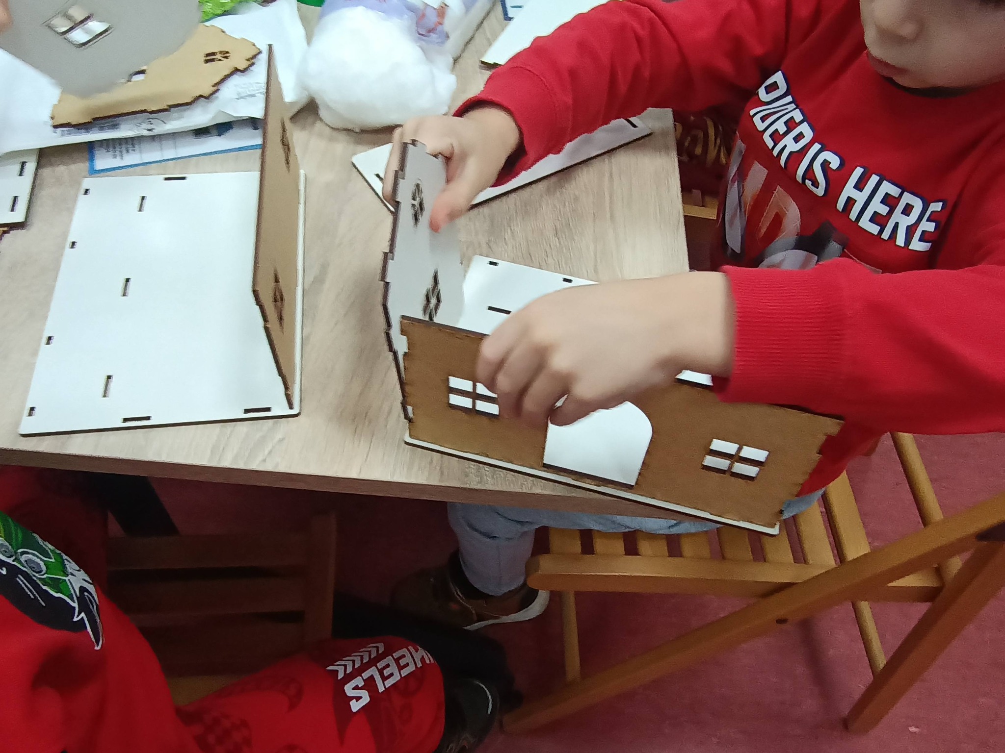 dziecko składa elementy drewnianego domku