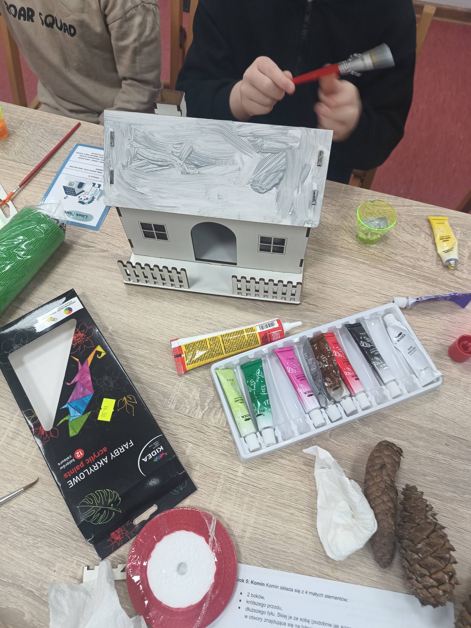 dziecko ozdabia domek w siwych kolorach