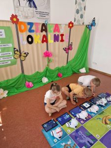 Na zdjęciu znajdują się dzieci, które sterują robotami w ramach projektu Działaj Lokalnie.